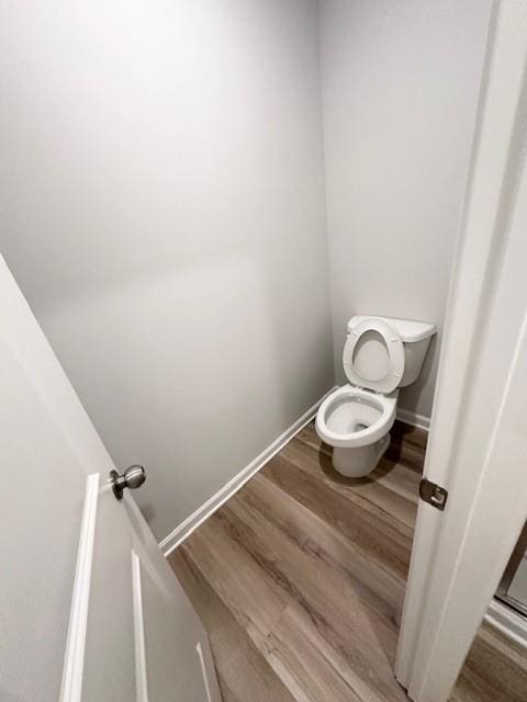 bathroom with baseboards, toilet, and wood finished floors