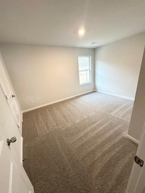 unfurnished room with baseboards and dark colored carpet