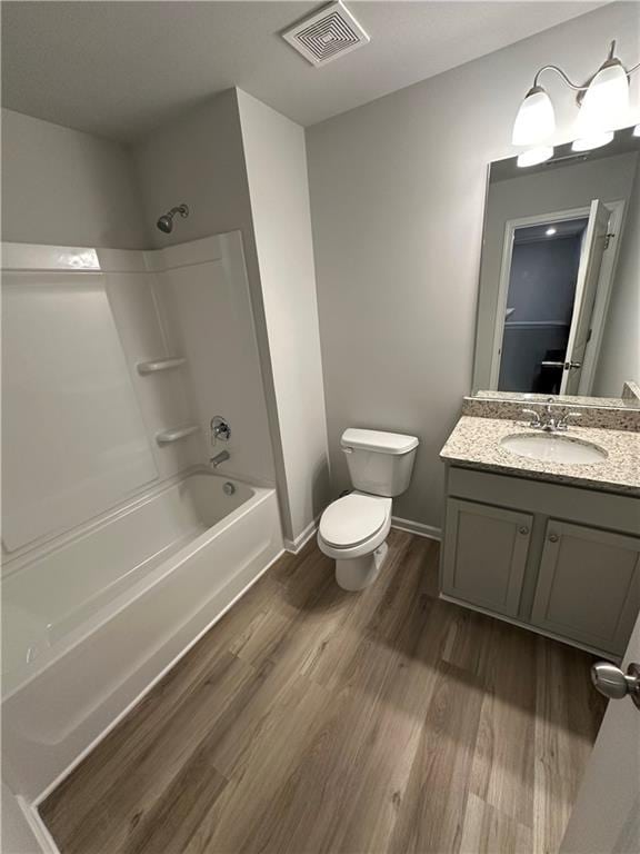 bathroom with visible vents, toilet, wood finished floors,  shower combination, and vanity