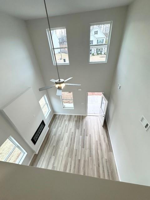 unfurnished living room with light wood-style floors, ceiling fan, and a fireplace