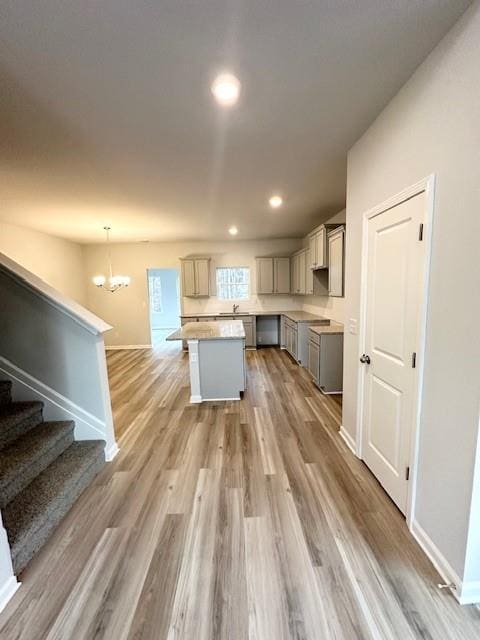 kitchen featuring light wood finished floors, a kitchen island, hanging light fixtures, gray cabinets, and light countertops