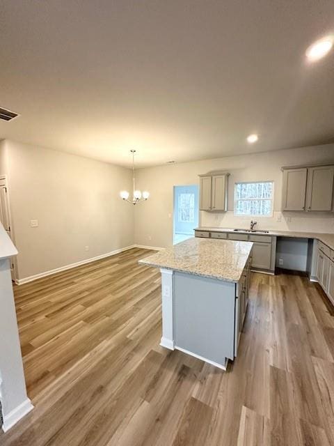 kitchen with gray cabinetry, wood finished floors, visible vents, hanging light fixtures, and a center island