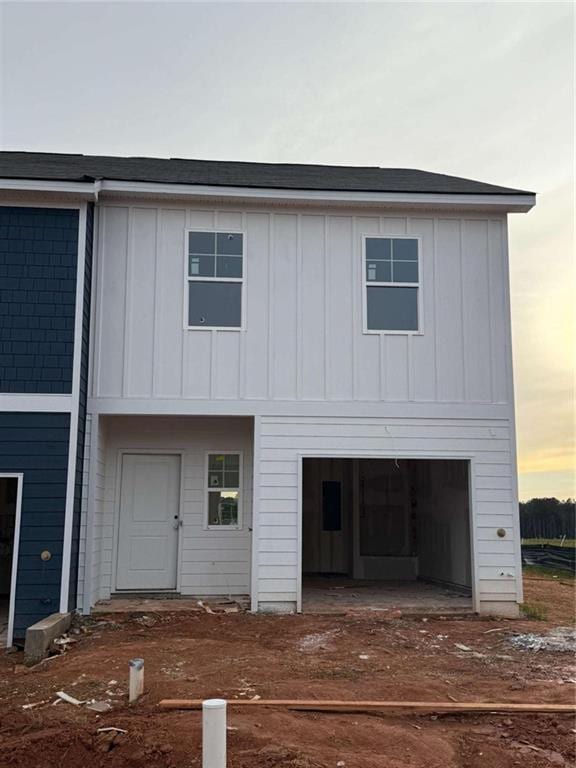 1346 Riverstone Rd Unit 107, Jonesboro, GA 30238 - back of property at dusk featuring board and batten siding, dirt driveway, and a garage
