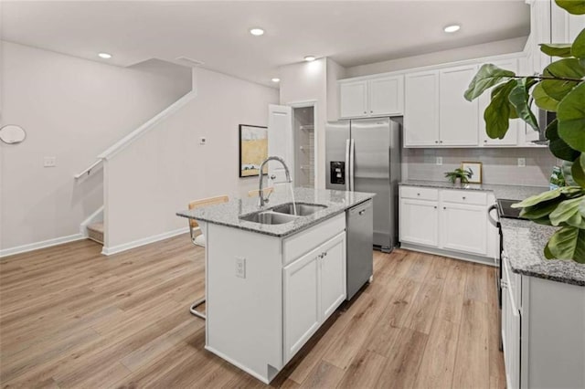 1346 Riverstone Rd Unit 107, Jonesboro, GA 30238 - kitchen featuring an island with sink, light stone countertops, stainless steel appliances, light wood finished floors, and a sink