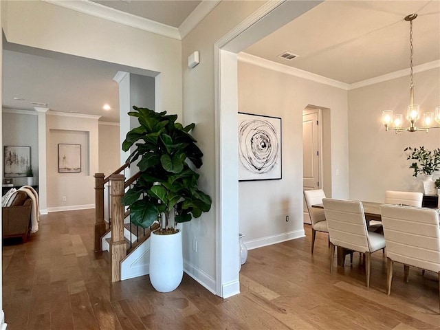 dining area with crown molding, hardwood / wood-style floors, and a notable chandelier