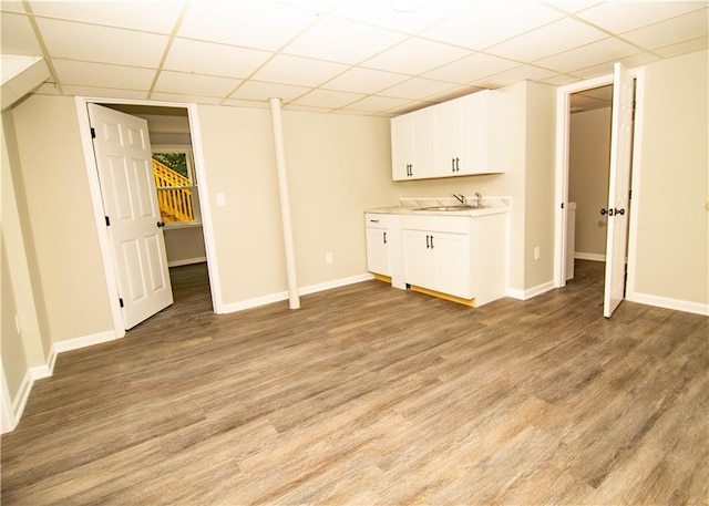 unfurnished living room featuring sink, a paneled ceiling, and light hardwood / wood-style floors