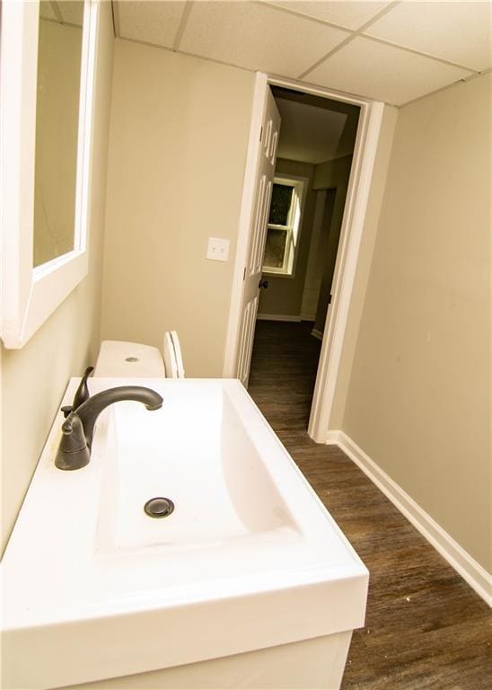 bathroom with hardwood / wood-style floors, a paneled ceiling, and sink