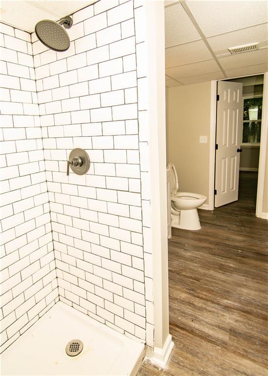 bathroom with a tile shower, hardwood / wood-style flooring, and toilet