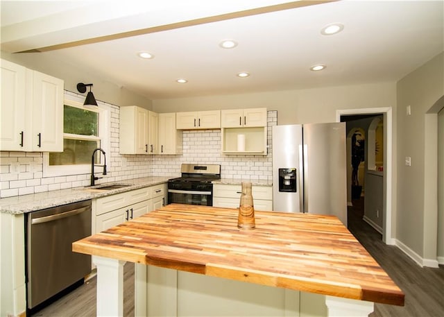 kitchen featuring sink, dark wood-type flooring, butcher block counters, stainless steel appliances, and decorative backsplash