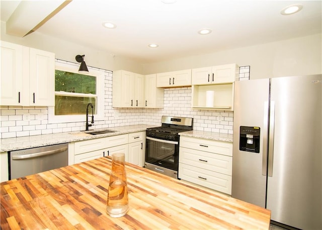 kitchen featuring butcher block counters, sink, backsplash, and stainless steel appliances