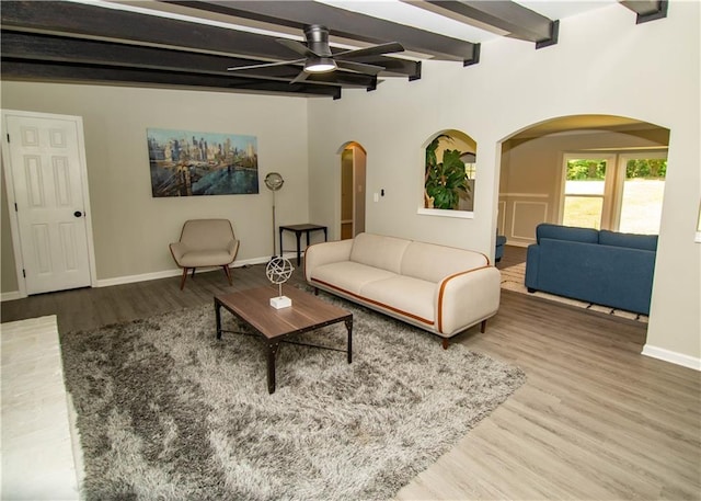 living room featuring beamed ceiling, wood-type flooring, and ceiling fan