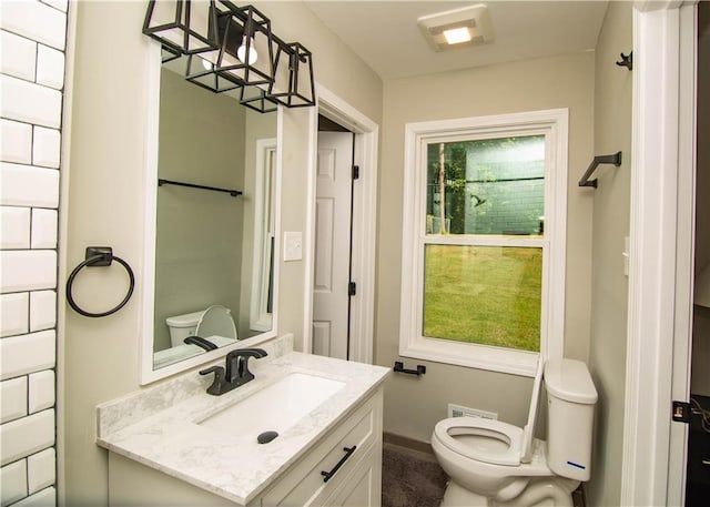 bathroom featuring a healthy amount of sunlight, vanity, and toilet