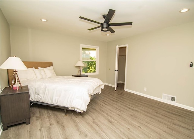 bedroom with ceiling fan, wood-type flooring, and a walk in closet