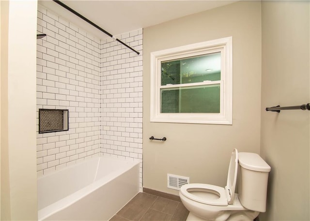 bathroom featuring tiled shower / bath combo, tile patterned flooring, and toilet