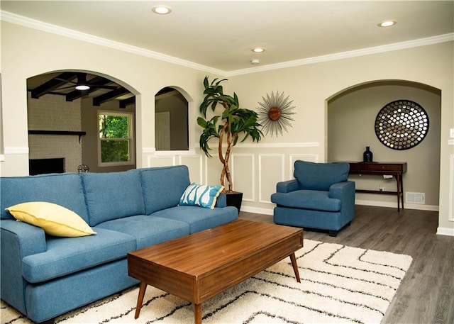 living room with wood-type flooring, crown molding, and a fireplace