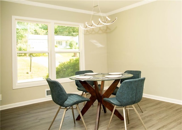 dining room with hardwood / wood-style floors, crown molding, and a notable chandelier