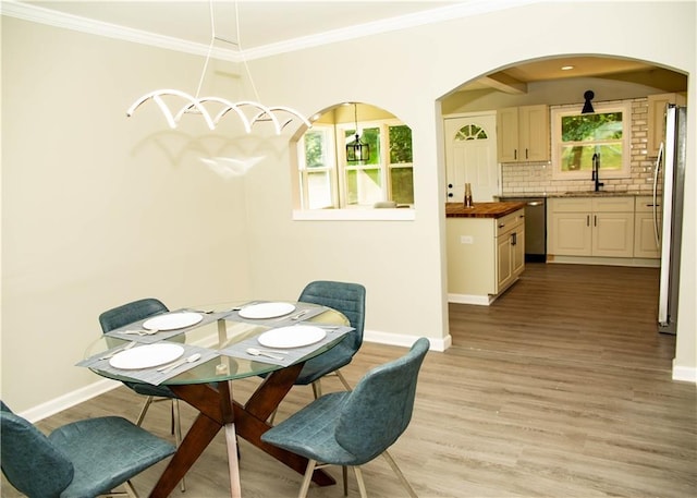 dining room featuring sink, crown molding, and light hardwood / wood-style floors