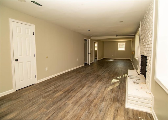 unfurnished living room featuring dark wood-type flooring and a brick fireplace