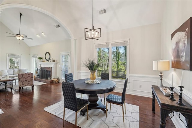 dining area featuring visible vents, arched walkways, wood finished floors, and a fireplace