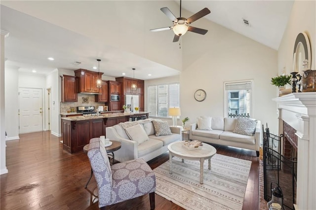 living room with visible vents, high vaulted ceiling, a ceiling fan, dark wood-style floors, and a fireplace