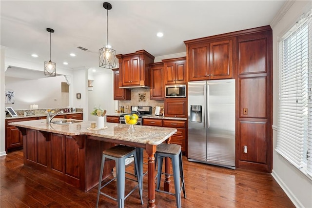 kitchen with light stone countertops, dark wood-style flooring, a sink, stainless steel appliances, and backsplash