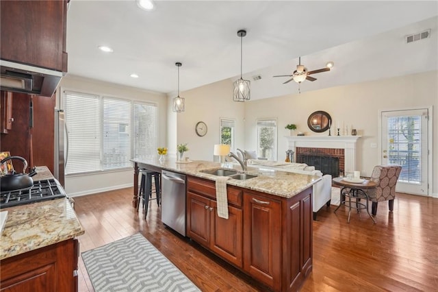 kitchen featuring visible vents, ceiling fan, dishwasher, a fireplace, and a sink