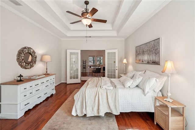 bedroom with visible vents, a tray ceiling, french doors, wood finished floors, and a ceiling fan