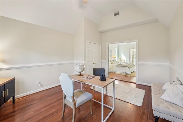 office area featuring visible vents, baseboards, wood finished floors, and vaulted ceiling