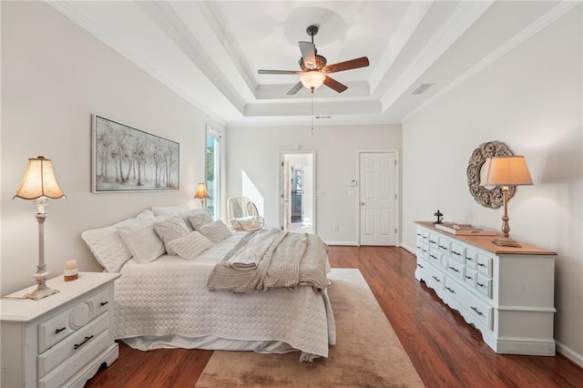 bedroom with a tray ceiling, crown molding, baseboards, and dark wood-type flooring