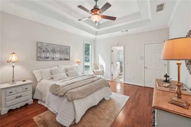 bedroom featuring a raised ceiling, ornamental molding, visible vents, and dark wood-type flooring