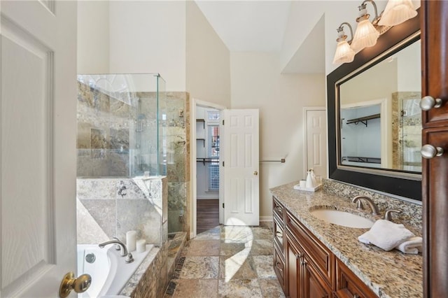 bathroom with a shower stall, baseboards, a bath, stone tile flooring, and vanity