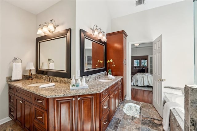 full bath with a sink, visible vents, double vanity, and stone finish floor