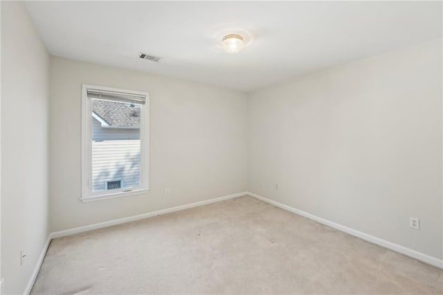 unfurnished room with visible vents, baseboards, and light colored carpet