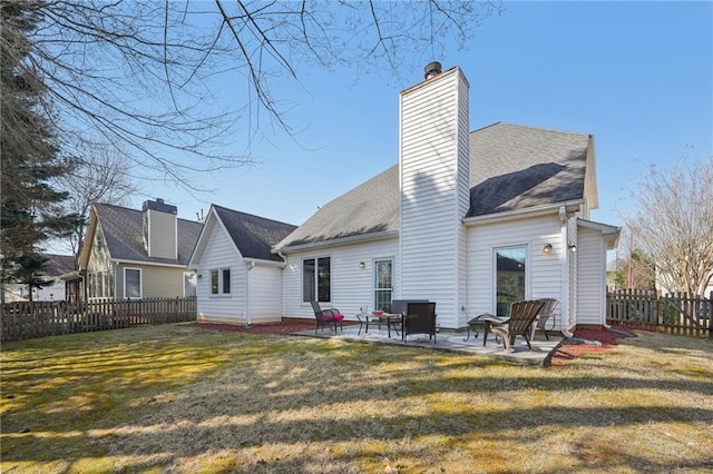 rear view of house featuring a patio, fence, a lawn, and a chimney