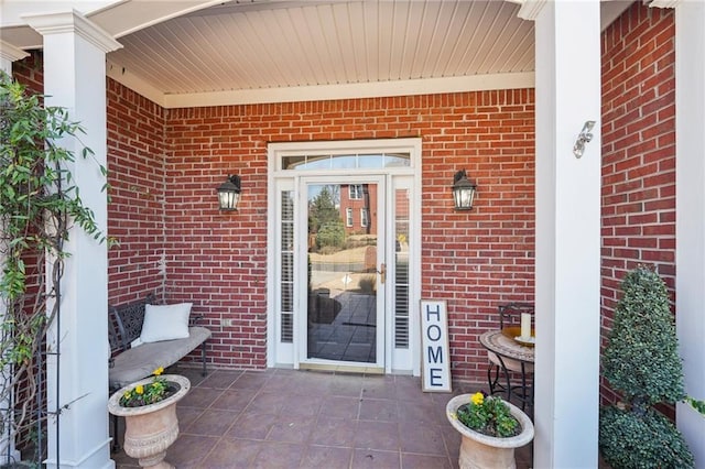 property entrance with a patio area and brick siding