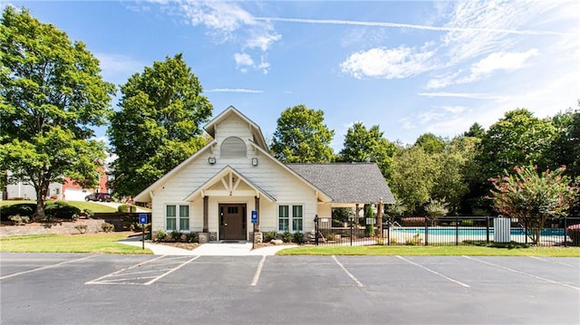 view of building exterior with a fenced in pool, uncovered parking, and fence