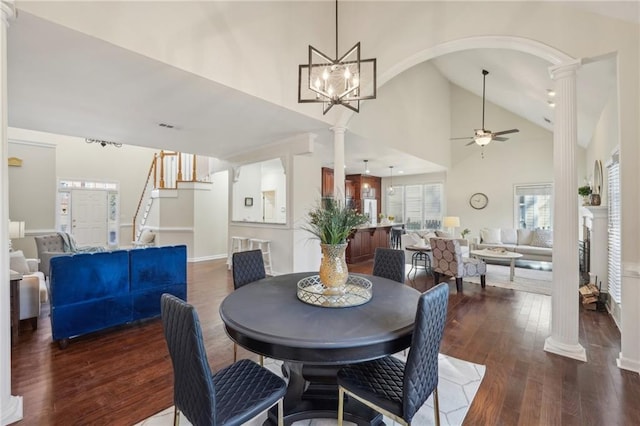 dining space featuring wood finished floors, a ceiling fan, high vaulted ceiling, decorative columns, and arched walkways