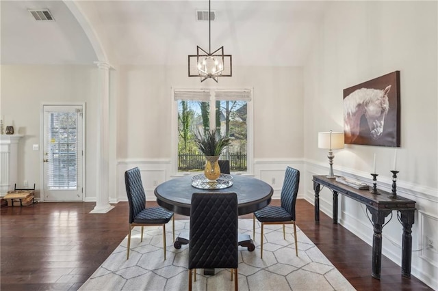 dining space with a wealth of natural light, visible vents, wood finished floors, and decorative columns