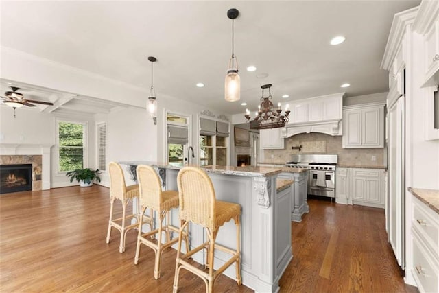 2539 Sagebrush Trl, Buford, GA 30519 - kitchen with double oven range, a warm lit fireplace, a ceiling fan, dark wood finished floors, and recessed lighting