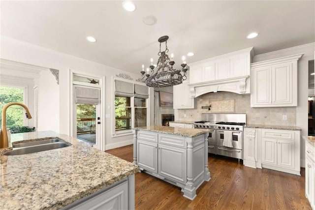 2539 Sagebrush Trl, Buford, GA 30519 - kitchen with range with two ovens, a center island, custom range hood, a chandelier, and white cabinetry