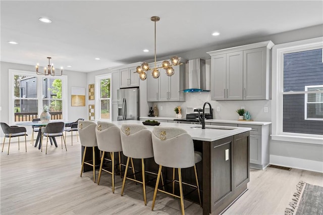 101 Fairfield Ct, Atlanta, GA 30314 - kitchen featuring wall chimney range hood, stainless steel appliances, a sink, a chandelier, and a center island with sink