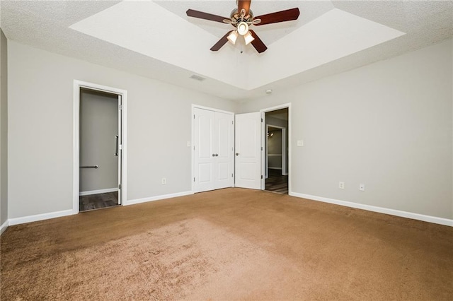 unfurnished bedroom featuring visible vents, baseboards, a raised ceiling, and carpet