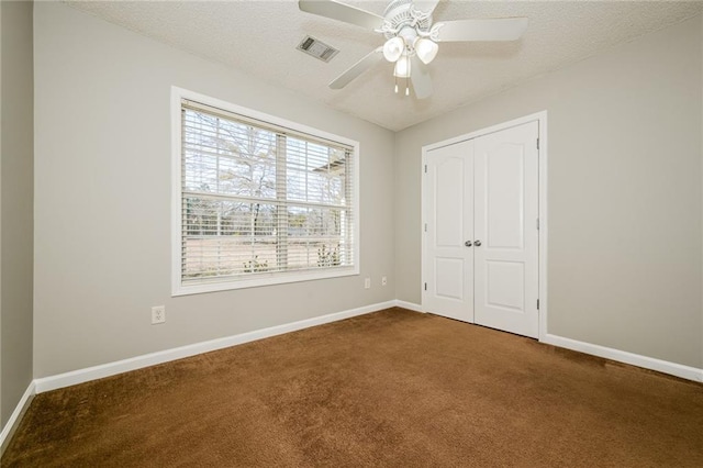 unfurnished bedroom with a closet, baseboards, visible vents, and dark colored carpet