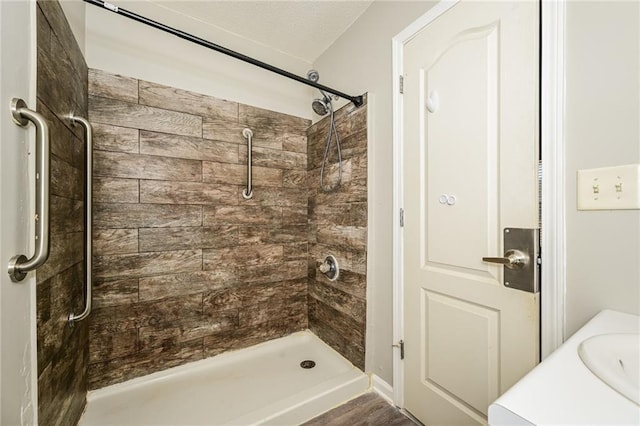 bathroom featuring a tile shower and a sink