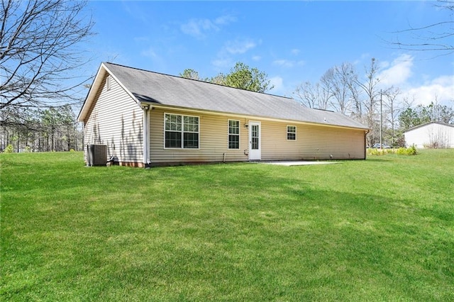 rear view of house featuring central AC unit and a lawn