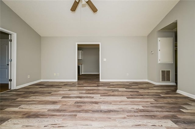 spare room with visible vents, baseboards, wood finished floors, and vaulted ceiling