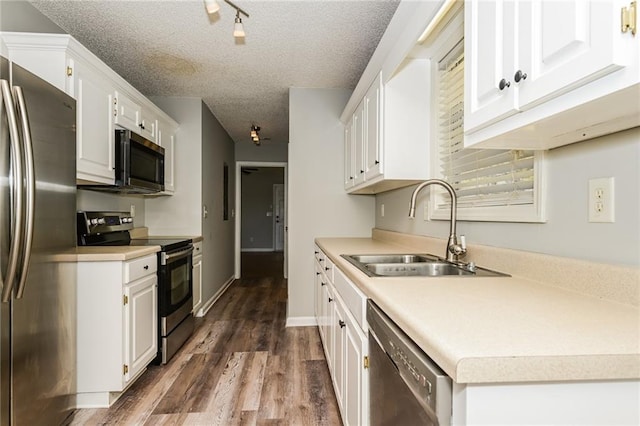 kitchen with dark wood-type flooring, a sink, a textured ceiling, white cabinetry, and appliances with stainless steel finishes