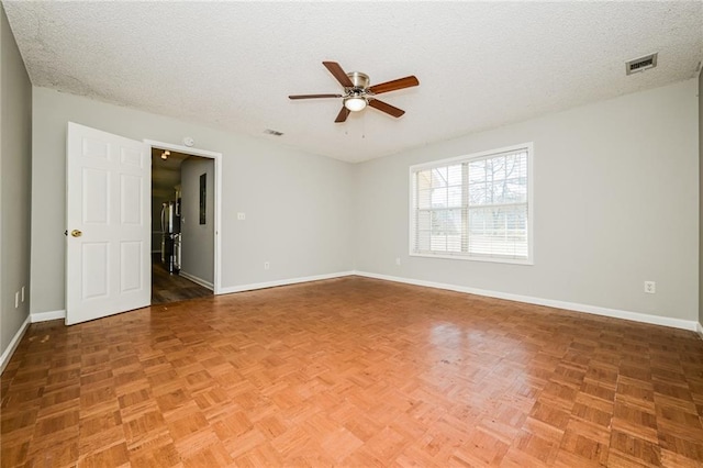 unfurnished room with visible vents, ceiling fan, a textured ceiling, and baseboards