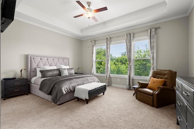 bedroom with ceiling fan, a tray ceiling, light carpet, and crown molding