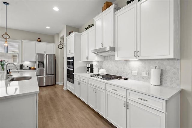 kitchen featuring light hardwood / wood-style flooring, decorative light fixtures, sink, appliances with stainless steel finishes, and white cabinetry